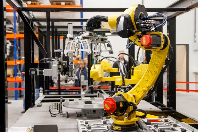 Six-axis robot in a guarded automated factory systems cell running closed-loop manufacturing autonomy within industrial automation